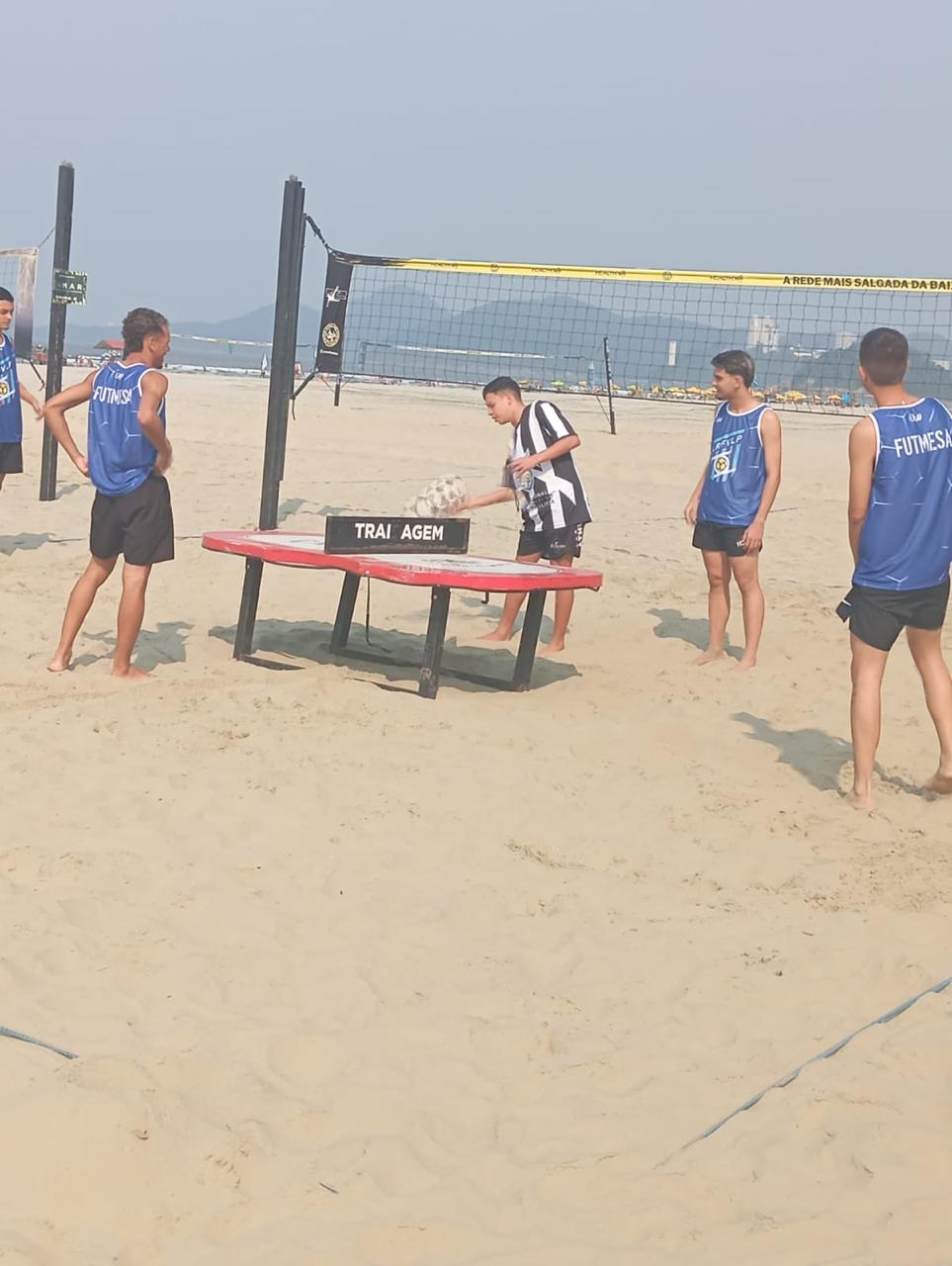 Jogadores de futevôlei treinando futmesa na areia da praia